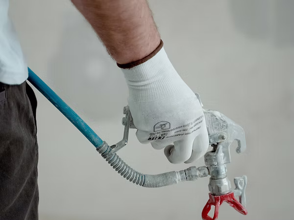 Worker holding an airless paint spray gun